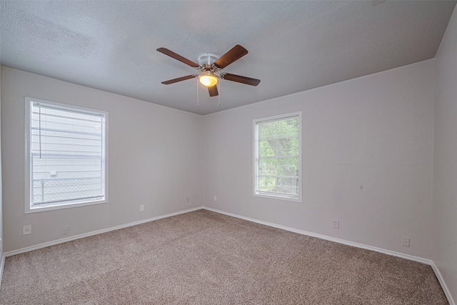 empty room with carpet flooring, baseboards, a ceiling fan, and a textured ceiling