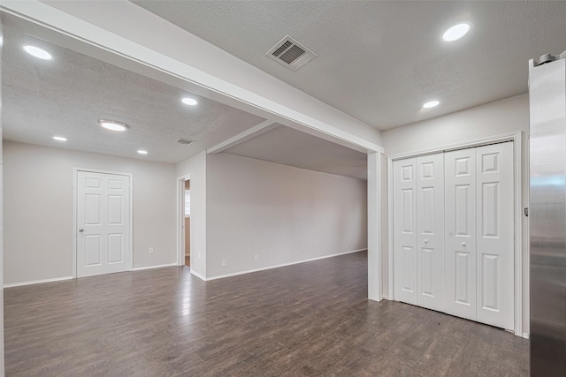 empty room with dark wood-style flooring, a textured ceiling, recessed lighting, and baseboards