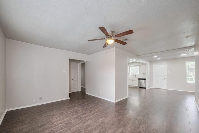 unfurnished living room featuring a ceiling fan, dark wood-style flooring, a textured ceiling, a sink, and baseboards