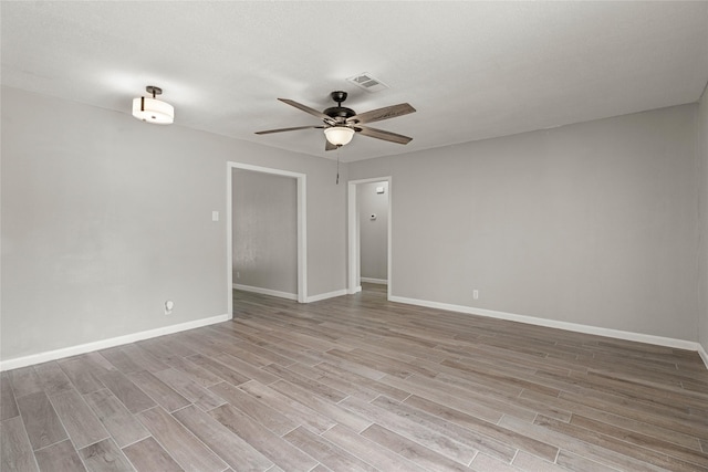 spare room featuring ceiling fan, light wood-style flooring, and baseboards