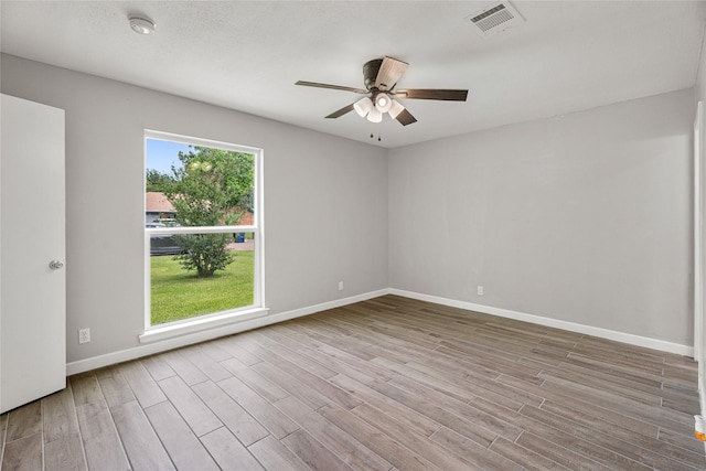 empty room with wood finished floors, a ceiling fan, baseboards, and a smoke detector