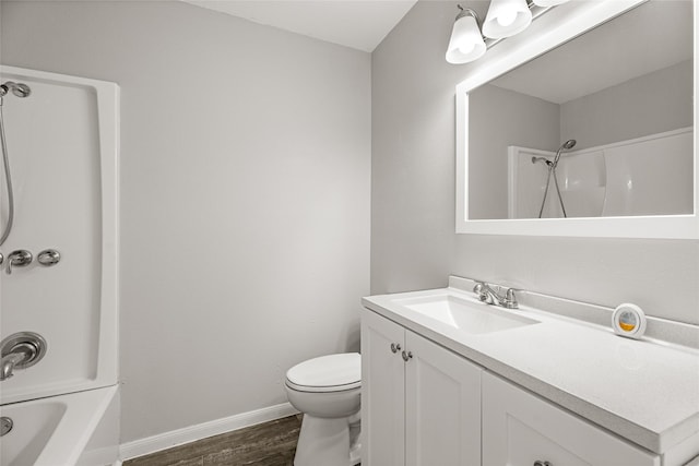 full bath with wood finished floors, toilet, baseboards, vanity, and shower / washtub combination