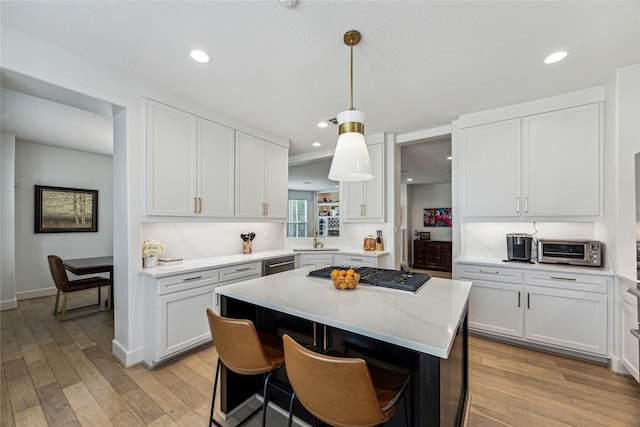 822 Reinicke St, Houston, TX 77007 - kitchen with stainless steel gas cooktop, a kitchen island, a sink, light wood finished floors, and recessed lighting