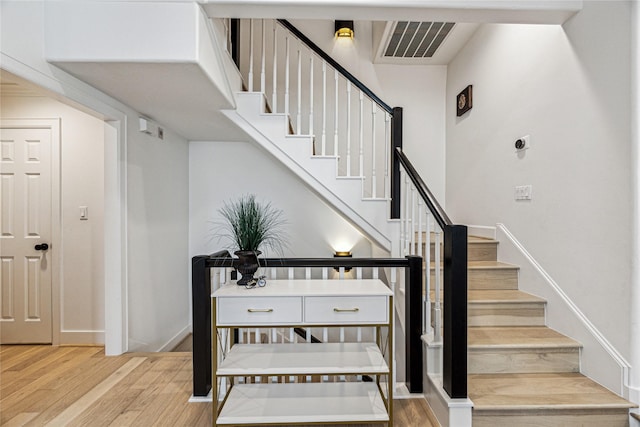 staircase featuring wood finished floors and baseboards