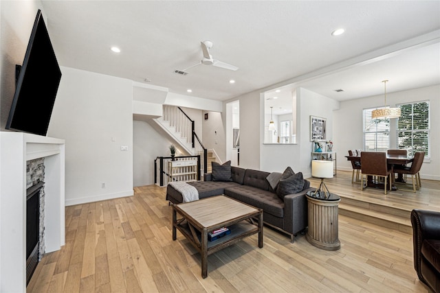 822 Reinicke St, Houston, TX 77007 - living room with light wood-type flooring, stairs, a stone fireplace, recessed lighting, and baseboards