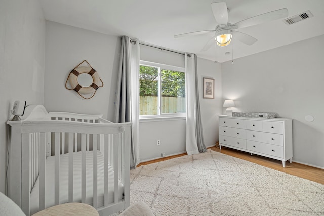 13 Leverwood Ct, The Woodlands, TX 77381 - bedroom featuring a crib, wood finished floors, and ceiling fan