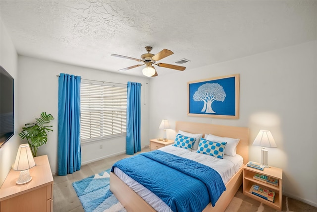 bedroom featuring baseboards, a ceiling fan, light colored carpet, and a textured ceiling