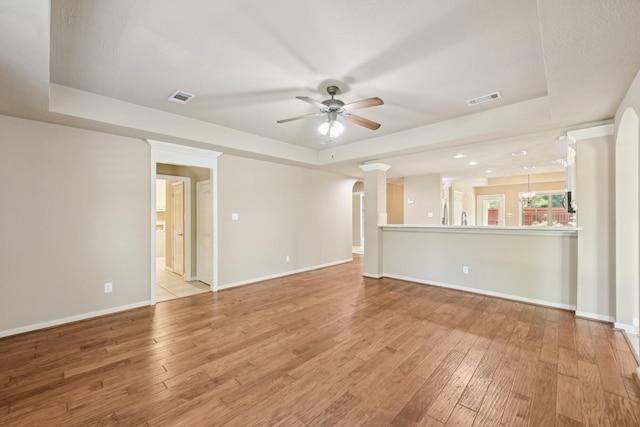 12885 Andromeda Ct, Willis, TX 77318 - unfurnished living room featuring a tray ceiling, a ceiling fan, light wood-style flooring, and baseboards