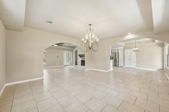12885 Andromeda Ct, Willis, TX 77318 - unfurnished living room featuring a chandelier, light tile patterned flooring, a fireplace with raised hearth, baseboards, and arched walkways