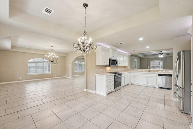12885 Andromeda Ct, Willis, TX 77318 - kitchen featuring appliances with stainless steel finishes, a chandelier, a sink, light countertops, and backsplash