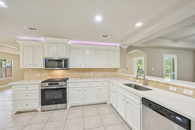 12885 Andromeda Ct, Willis, TX 77318 - kitchen with stainless steel appliances, a sink, light tile patterned flooring, tasteful backsplash, and arched walkways