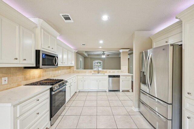 12885 Andromeda Ct, Willis, TX 77318 - kitchen with stainless steel appliances, a sink, ceiling fan, backsplash, and light tile patterned floors