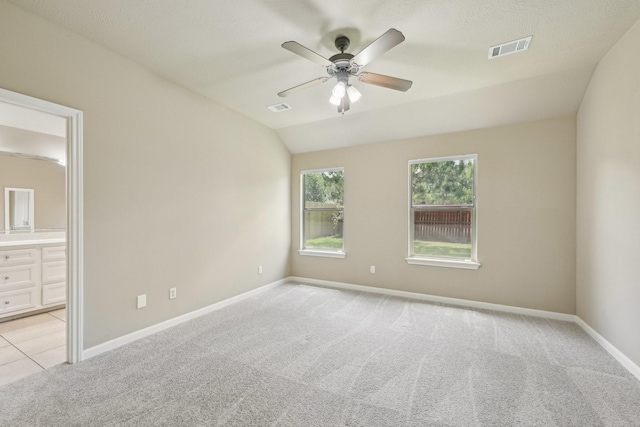 12885 Andromeda Ct, Willis, TX 77318 - unfurnished bedroom with light colored carpet, baseboards, connected bathroom, lofted ceiling, and a ceiling fan