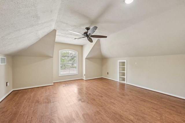 12885 Andromeda Ct, Willis, TX 77318 - bonus room featuring a textured ceiling, vaulted ceiling, wood finished floors, ceiling fan, and baseboards