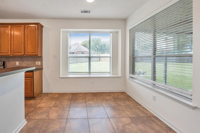 12139 Canyon Arbor Way, Houston, TX 77095 - kitchen featuring brown cabinets, decorative backsplash, tile patterned floors, and baseboards