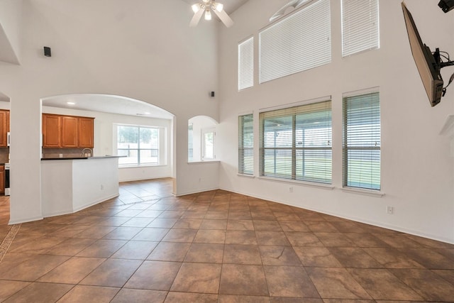12139 Canyon Arbor Way, Houston, TX 77095 - unfurnished living room with a ceiling fan, a towering ceiling, arched walkways, tile patterned flooring, and baseboards