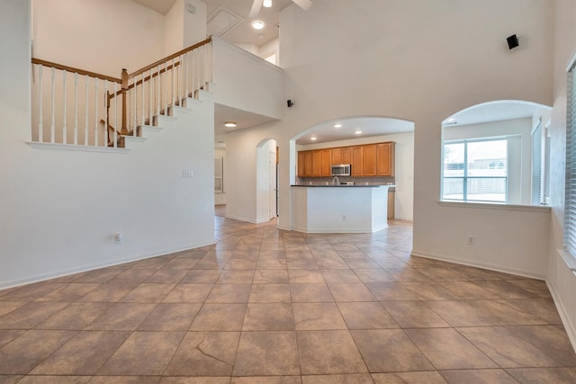 12139 Canyon Arbor Way, Houston, TX 77095 - unfurnished living room with arched walkways, a high ceiling, baseboards, and stairway