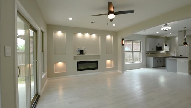 2716 Garapan St, Houston, TX 77091 - unfurnished living room featuring a glass covered fireplace, baseboards, light wood-type flooring, ceiling fan, and recessed lighting