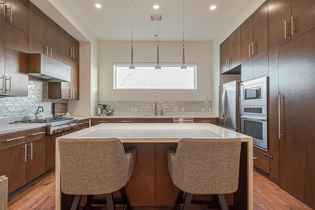 1510 Yale St Unit B, Houston, TX 77008 - kitchen featuring stainless steel appliances, a breakfast bar, light wood-style floors, a sink, and tasteful backsplash