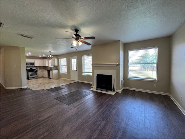 3505 Stonegate Cir, Pearland, TX 77584 - unfurnished living room featuring a ceiling fan, baseboards, a textured ceiling, wood finished floors, and a fireplace with flush hearth