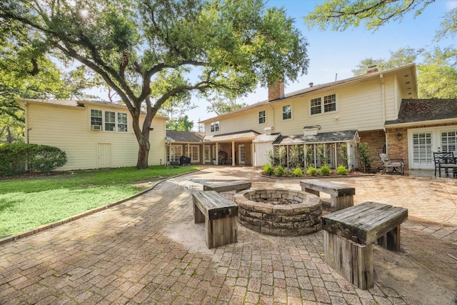 back of house with an outdoor fire pit, a chimney, a patio, brick siding, and a lawn