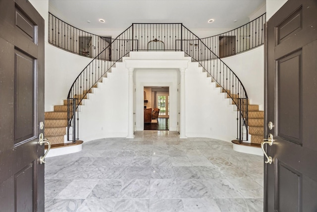 foyer with stairs, a high ceiling, baseboards, light marble finish flooring, and recessed lighting