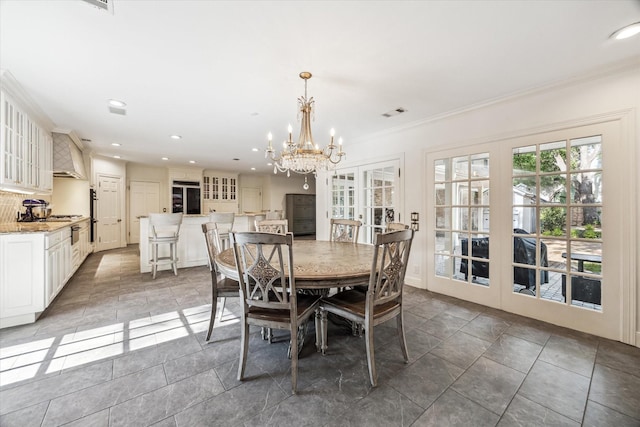 dining room with french doors, a chandelier, ornamental molding, recessed lighting, and stone finish floors