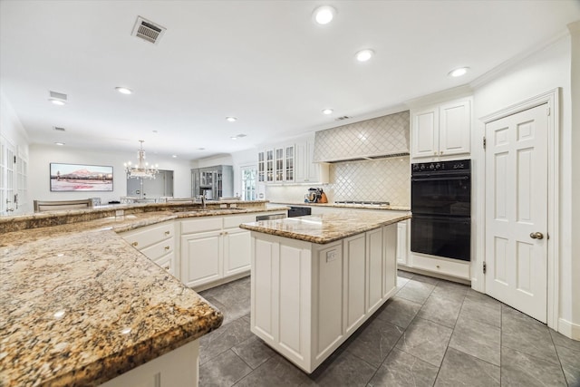 kitchen with black appliances, a chandelier, backsplash, white cabinets, and light stone counters