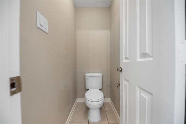 bathroom with tile patterned floors, toilet, and baseboards