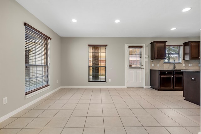 kitchen with recessed lighting, backsplash, dark brown cabinetry, baseboards, and a sink