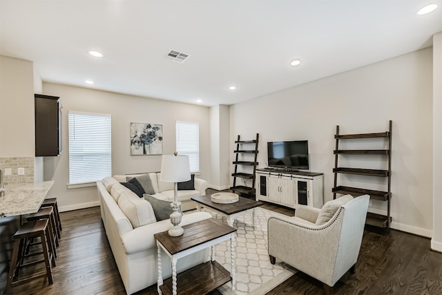 living room with dark wood-type flooring, baseboards, and recessed lighting