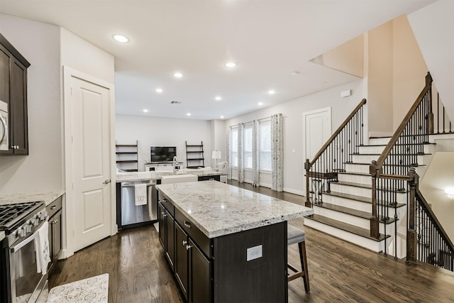 kitchen with stainless steel appliances, dark wood finished floors, a kitchen island, a kitchen breakfast bar, and recessed lighting
