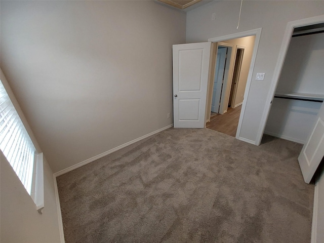 unfurnished bedroom with carpet floors, baseboards, a closet, and attic access