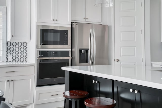 30142 Gold Finch Pl, Fulshear, TX 77441 - kitchen with stainless steel appliances, light countertops, tasteful backsplash, white cabinetry, and a breakfast bar area