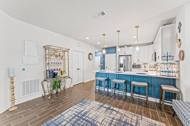 6804 Westview Dr Unit 2207, Houston, TX 77055 - kitchen with stainless steel fridge with ice dispenser, wood finish floors, white cabinets, a peninsula, and recessed lighting