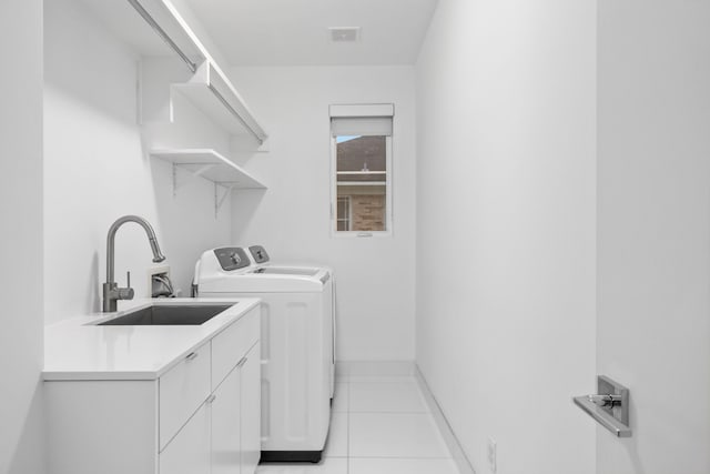 laundry room featuring separate washer and dryer, cabinet space, light tile patterned floors, and baseboards