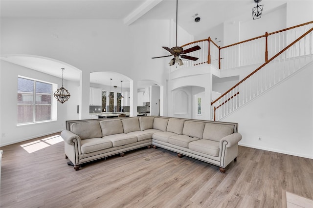 16219 Haden Crest Ct, Cypress, TX 77429 - living room with a ceiling fan, light wood-type flooring, arched walkways, baseboards, and a towering ceiling