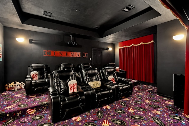carpeted cinema room with a raised ceiling and baseboards
