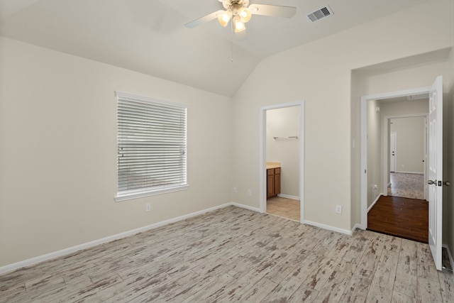 unfurnished bedroom featuring light wood finished floors, vaulted ceiling, baseboards, ensuite bath, and a ceiling fan
