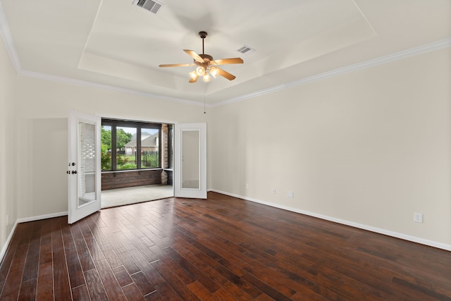 spare room featuring a raised ceiling, dark wood-style floors, ceiling fan, baseboards, and crown molding