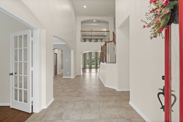 entryway with arched walkways, a towering ceiling, recessed lighting, and baseboards