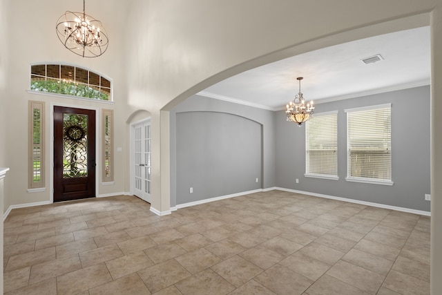 foyer with a chandelier, arched walkways, baseboards, and ornamental molding