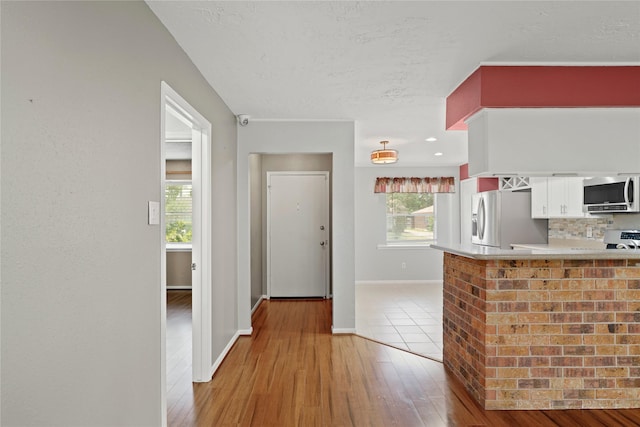 21410 Glenbranch Dr, Spring, TX 77388 - kitchen featuring appliances with stainless steel finishes, white cabinets, light wood-style floors, light countertops, and baseboards