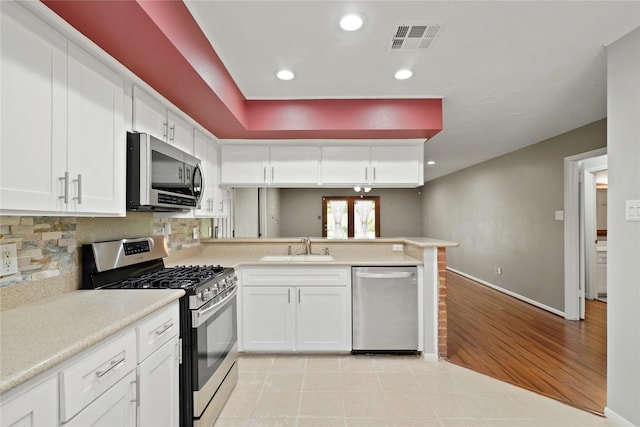 21410 Glenbranch Dr, Spring, TX 77388 - kitchen featuring stainless steel appliances, a peninsula, a sink, light countertops, and decorative backsplash