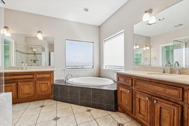 bathroom featuring a stall shower, a garden tub, two vanities, and tile patterned flooring
