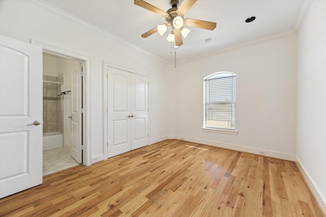 unfurnished bedroom featuring light wood-style flooring, crown molding, baseboards, a closet, and ensuite bath
