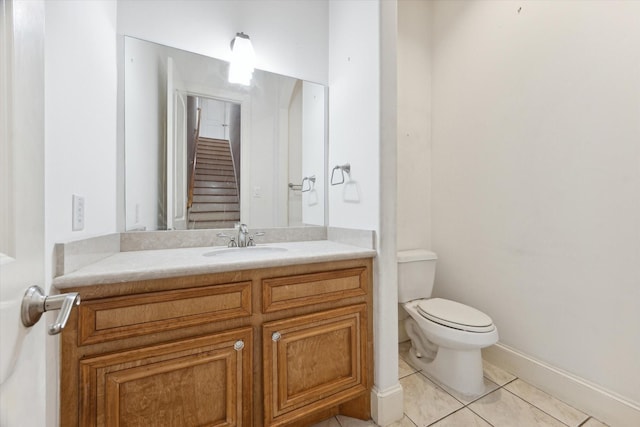 bathroom featuring toilet, vanity, tile patterned floors, and baseboards