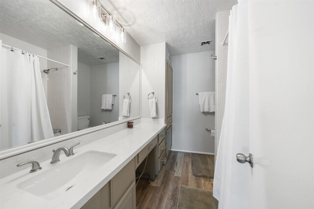 1924 Clipper Ct, Willis, TX 77318 - bathroom featuring wood finished floors, a textured ceiling, vanity, a shower with shower curtain, and toilet