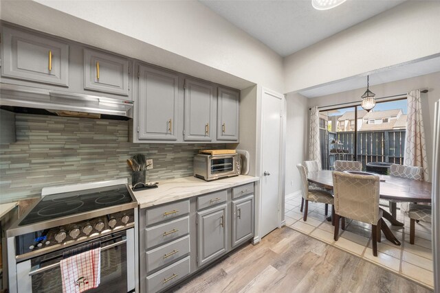 1924 Clipper Ct, Willis, TX 77318 - kitchen with gray cabinetry, stainless steel stove, under cabinet range hood, decorative backsplash, and light wood-style flooring