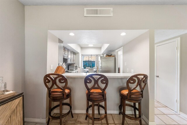 1924 Clipper Ct, Willis, TX 77318 - kitchen featuring freestanding refrigerator, a breakfast bar, light countertops, baseboards, and recessed lighting
